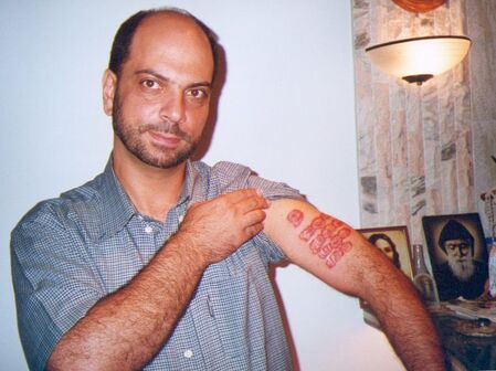 Photo of Raymond Nader with the imprint of St Sharbel's five fingers visible on his my forearm.